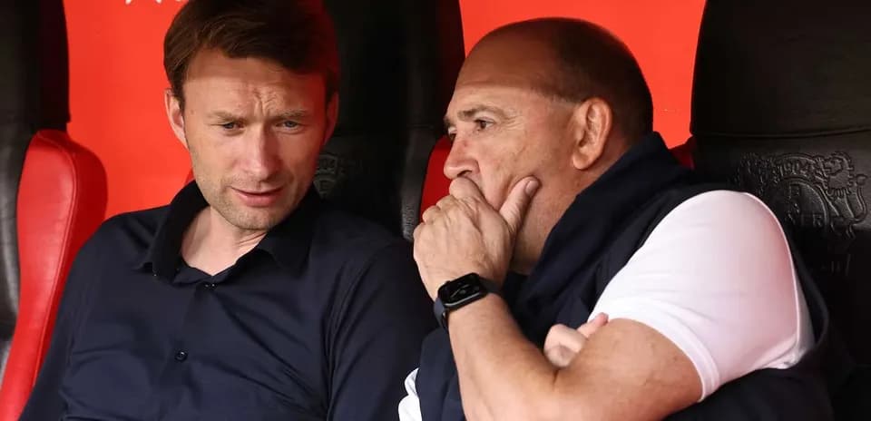 Two coaches discussing on the bench during match