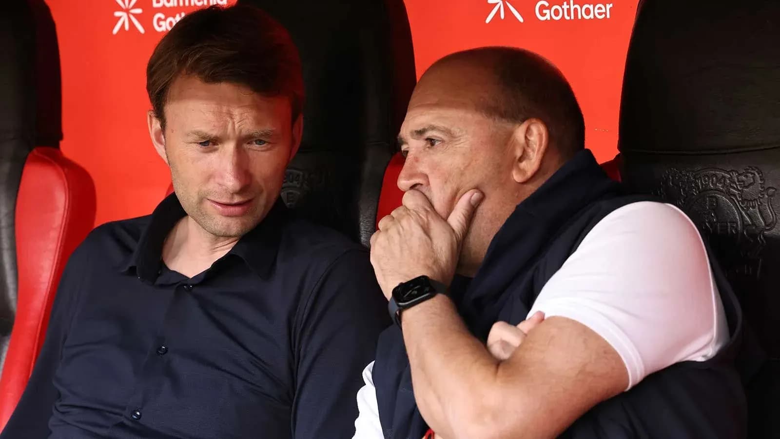 Two coaches discussing on the bench during match