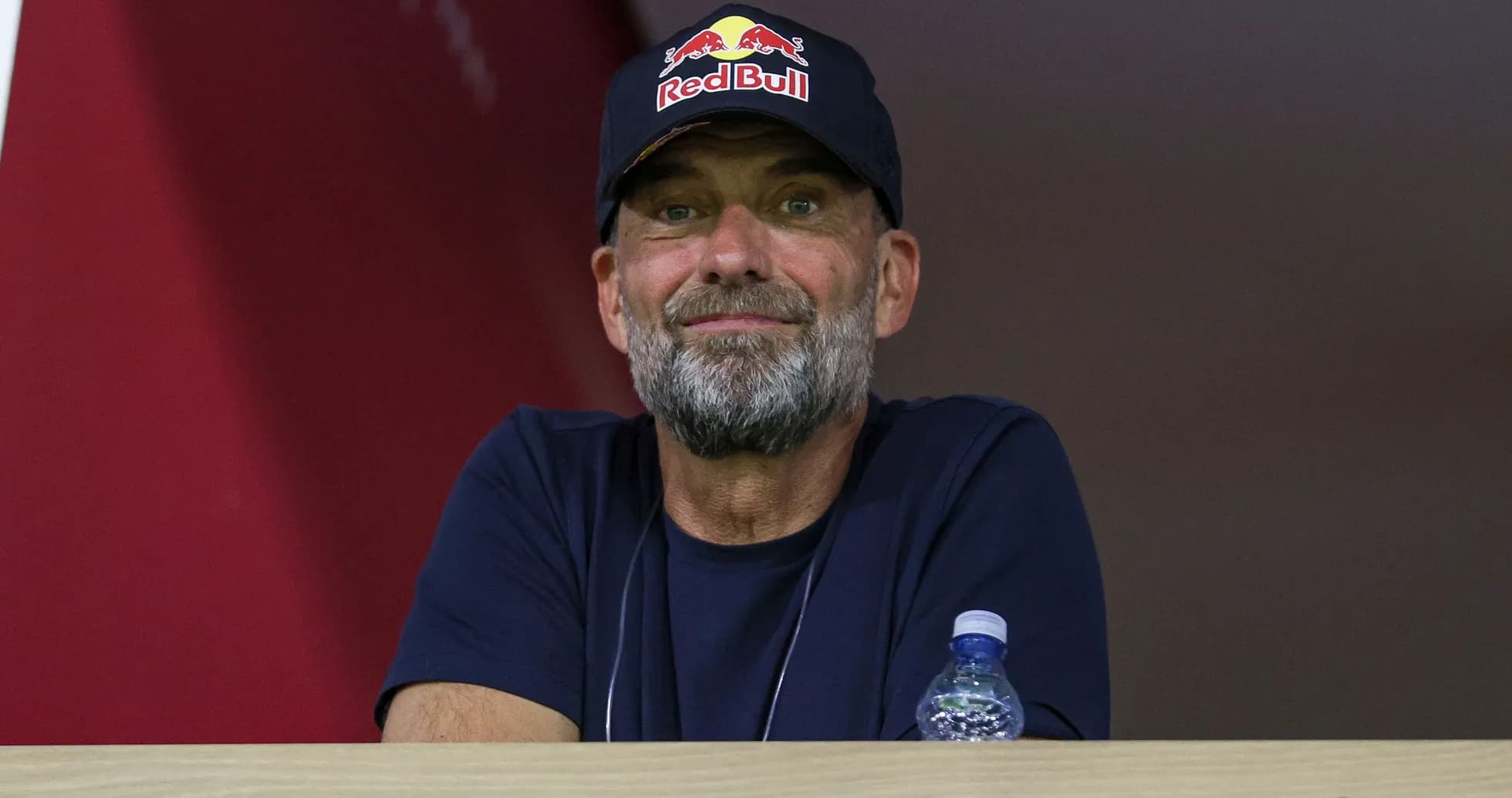 Man with beard wearing Red Bull cap in stands
