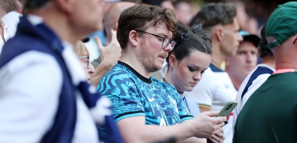 Fans looking at their phones in crowded stadium