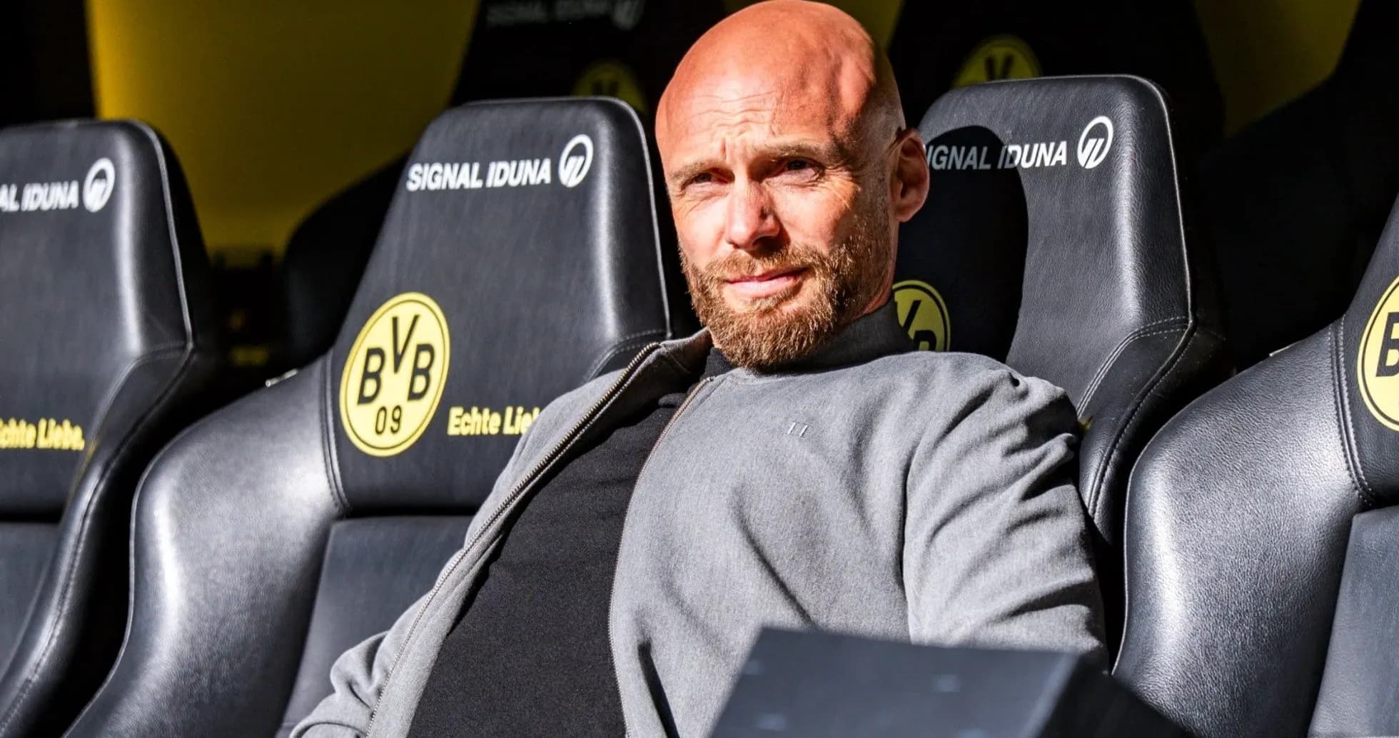 Coach sitting on bench at stadium with team logo