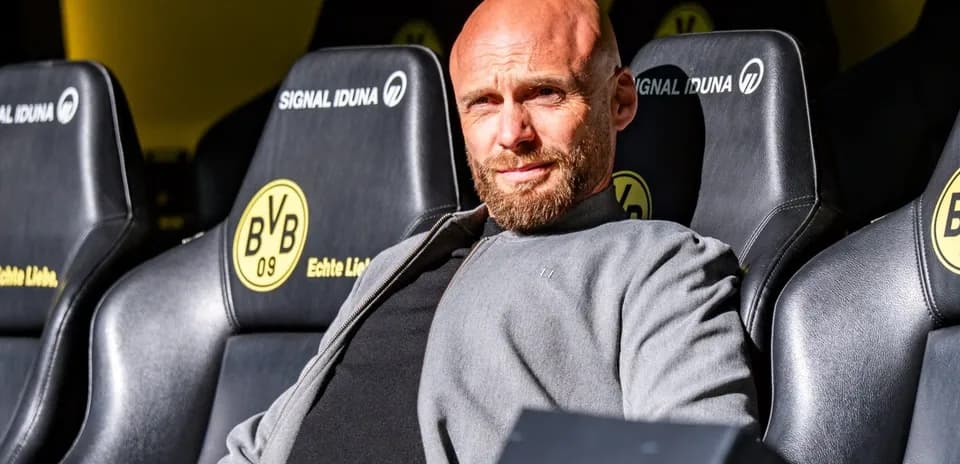 Coach sitting on bench at stadium with team logo