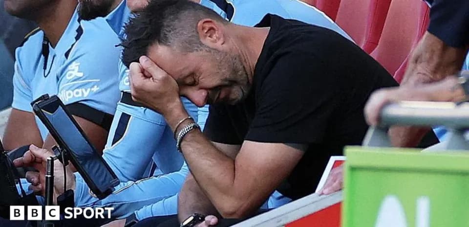 Coach sitting on bench with hand on forehead