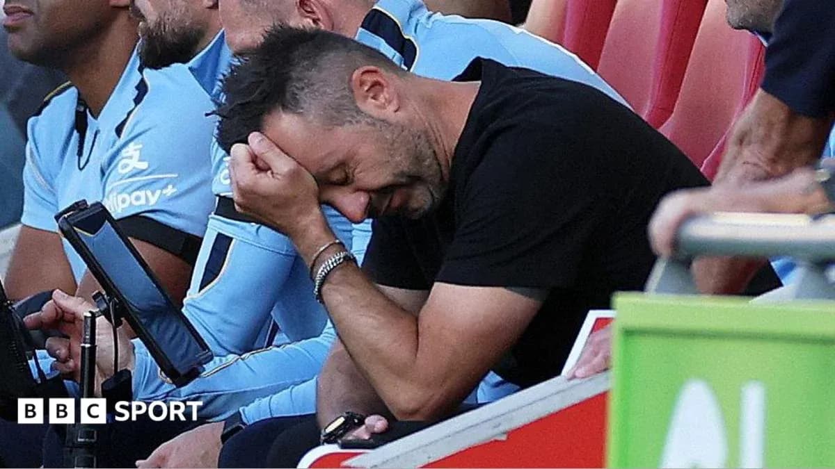 Coach sitting on bench with hand on forehead