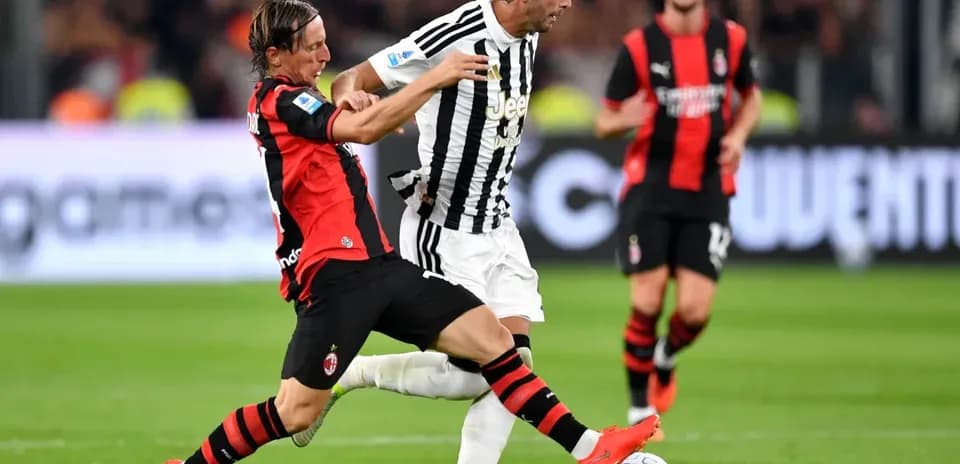 Player from AC Milan tackles Juventus player during match