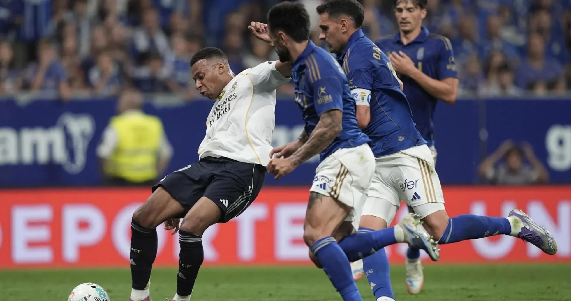 Real Madrid player challenged by Oviedo defenders