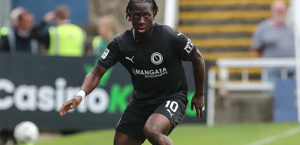 Player in black kit dribbling on the field