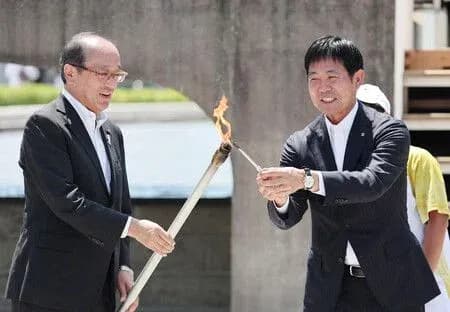 Two men exchanging a torch during ceremony