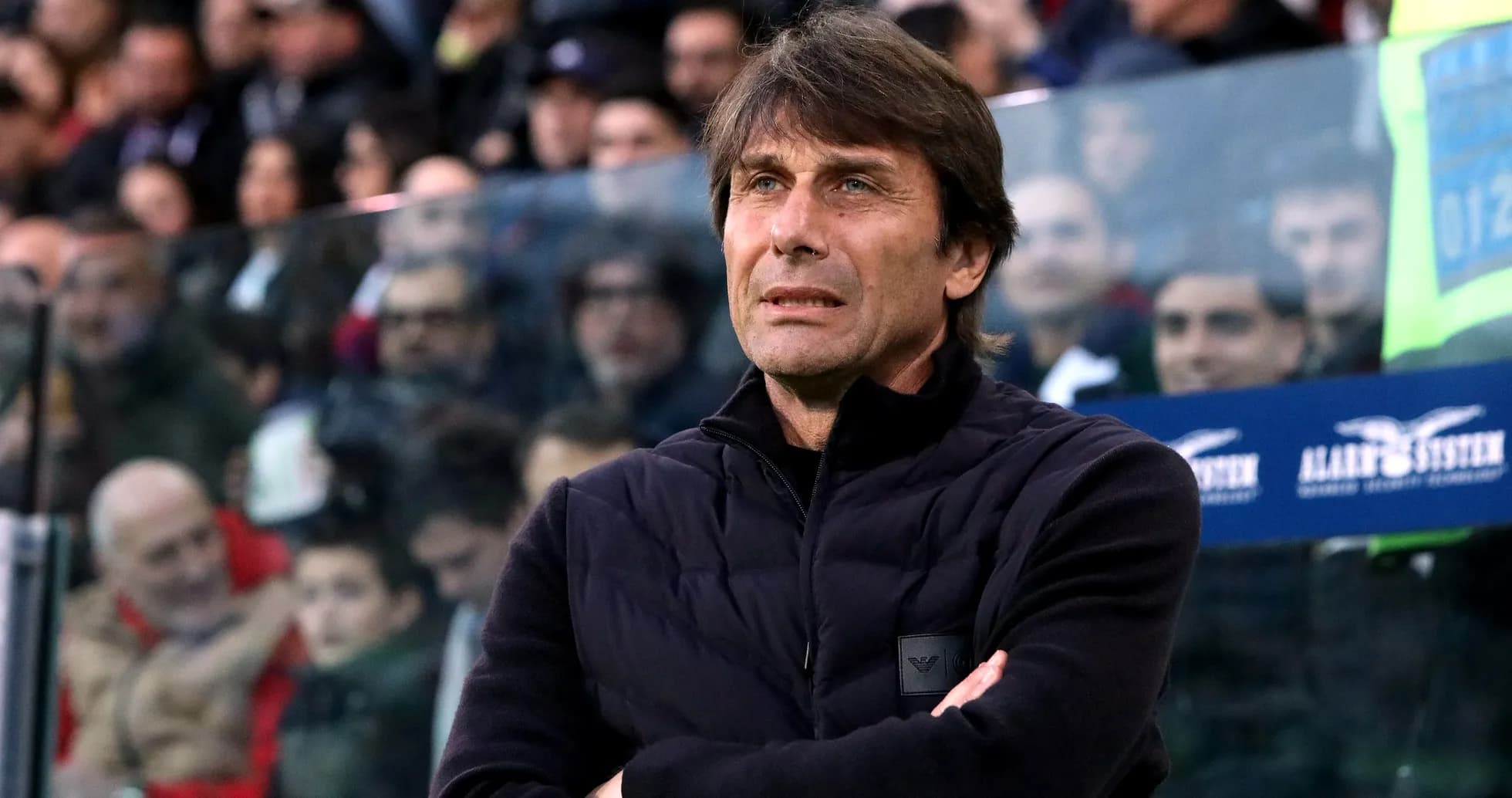 Coach observing match with arms crossed in stadium