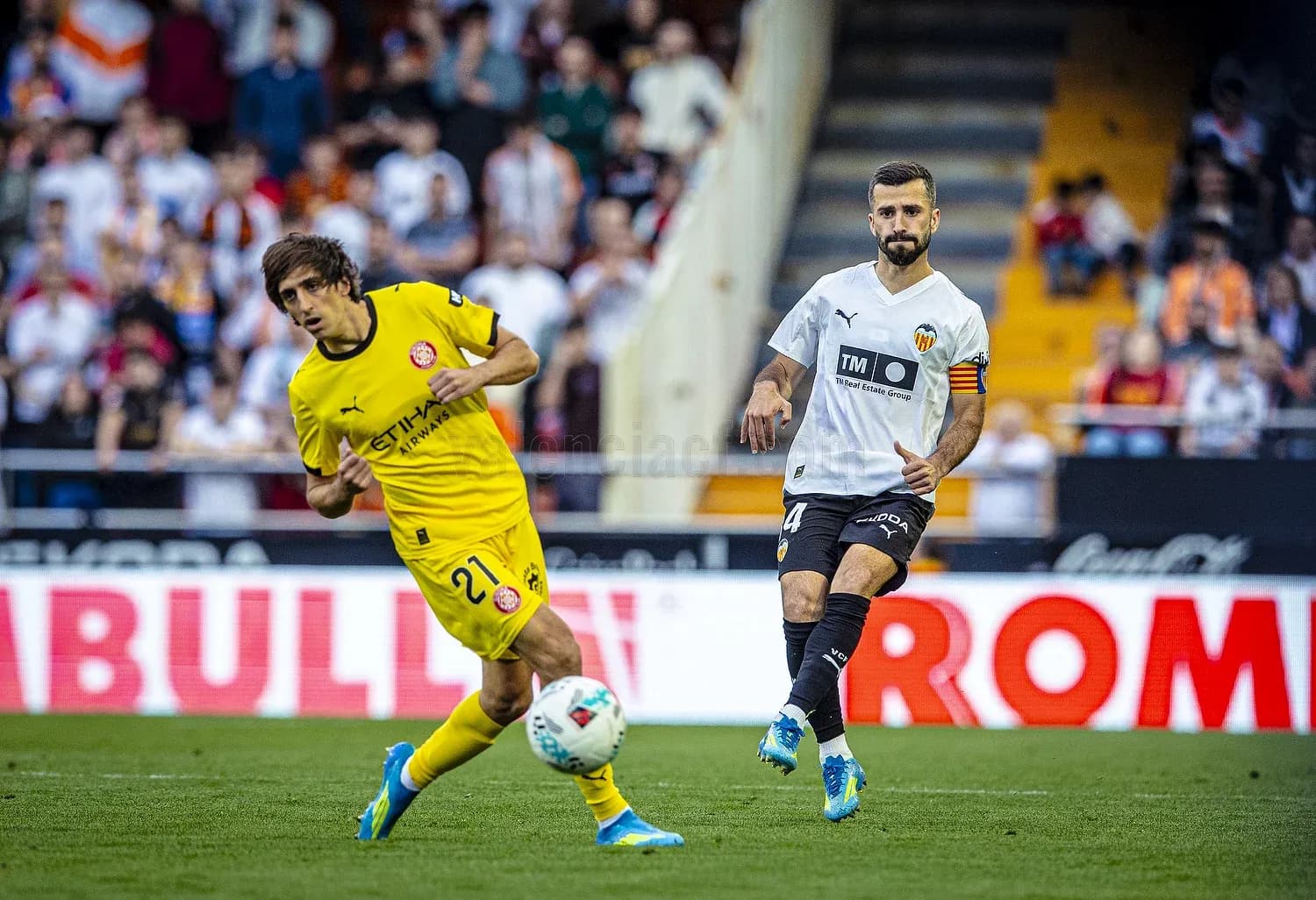 Valencia player challenges Girona player for ball