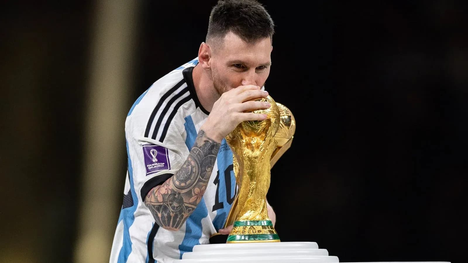 Player kissing FIFA World Cup trophy on podium