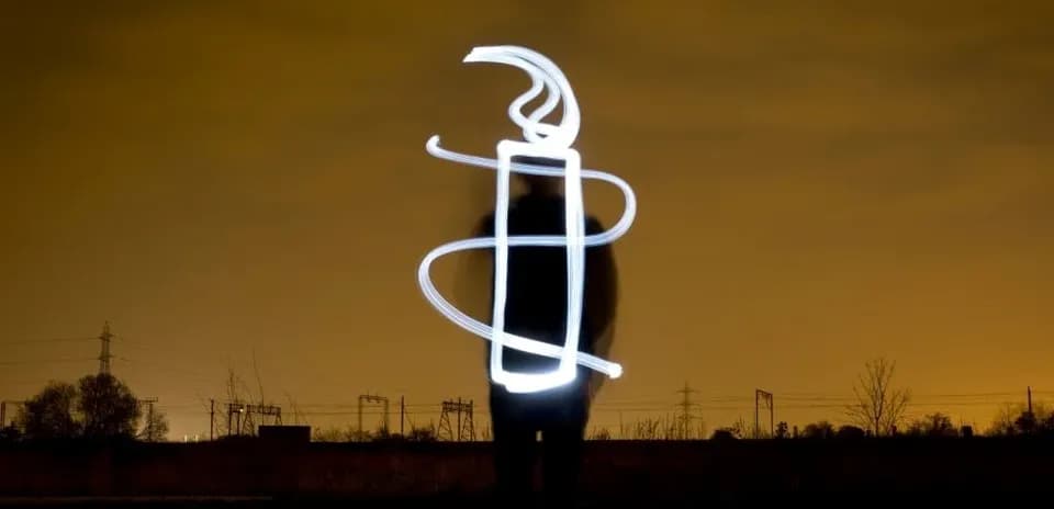 Person creating light drawing in night landscape