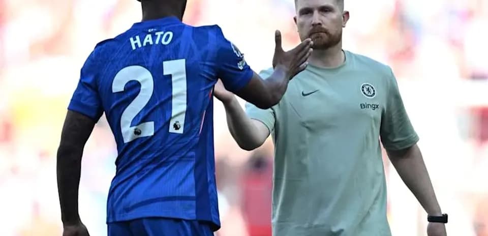 Player in blue jersey greeting staff member on pitch