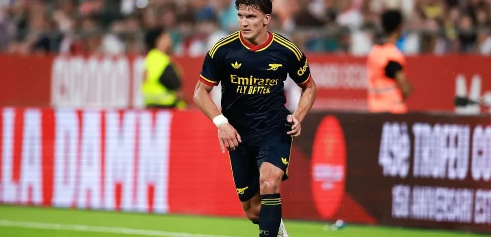 Player in Arsenal kit dribbling ball on pitch