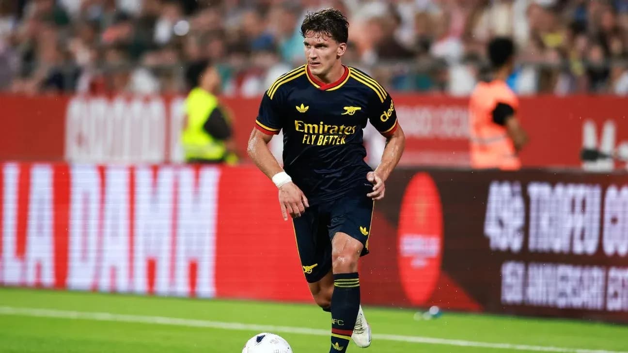 Player in Arsenal kit dribbling ball on pitch