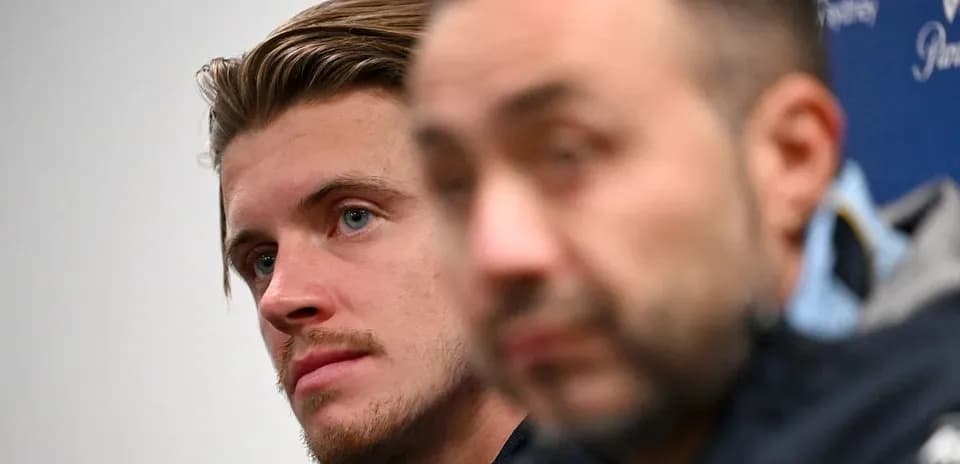 Two men at a press conference, one in focus