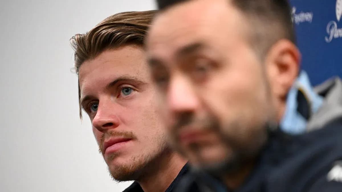 Two men at a press conference, one in focus