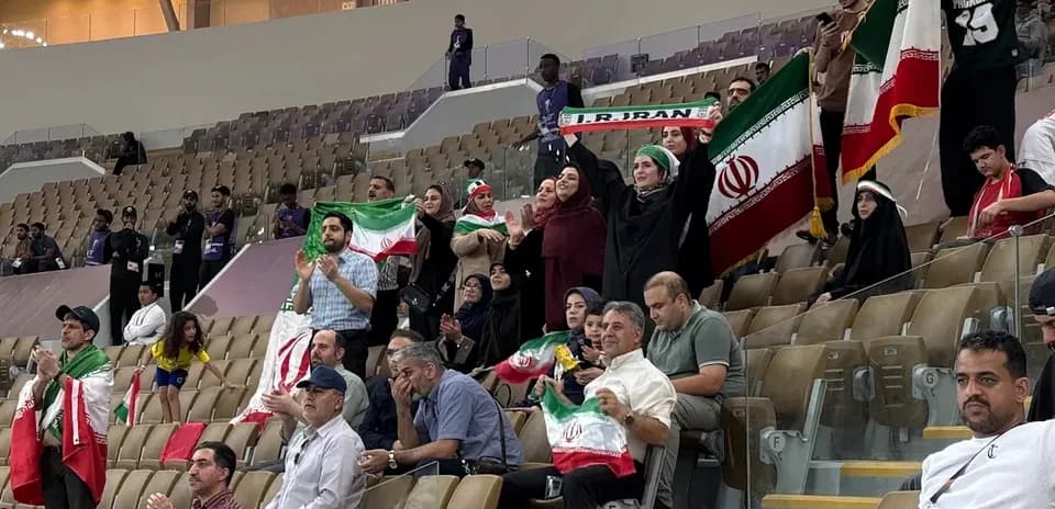 Iranian fans cheering and waving flags in stadium