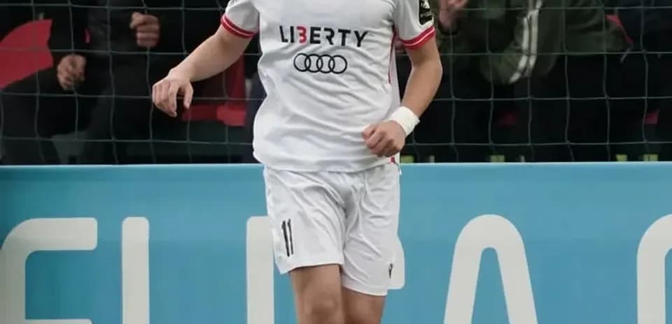 Player in white kit dribbling soccer ball on field