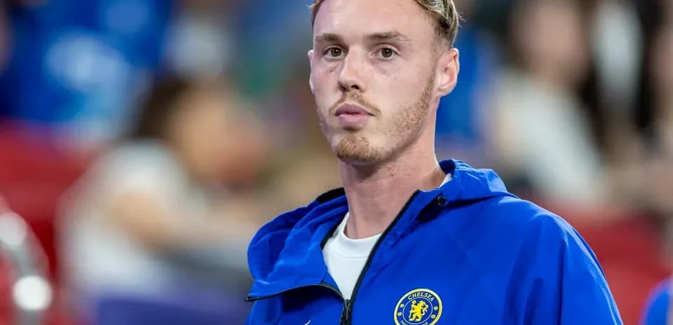 Chelsea player in blue jacket on sidelines