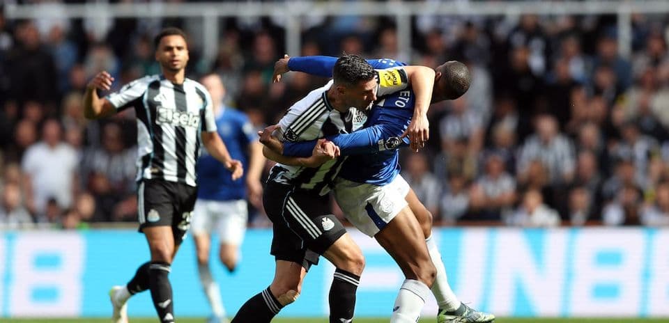 Newcastle player tackling Everton opponent during match