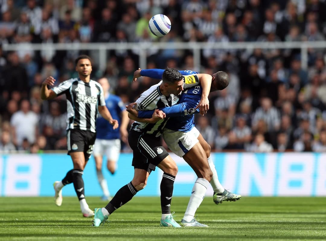 Newcastle player tackling Everton opponent during match