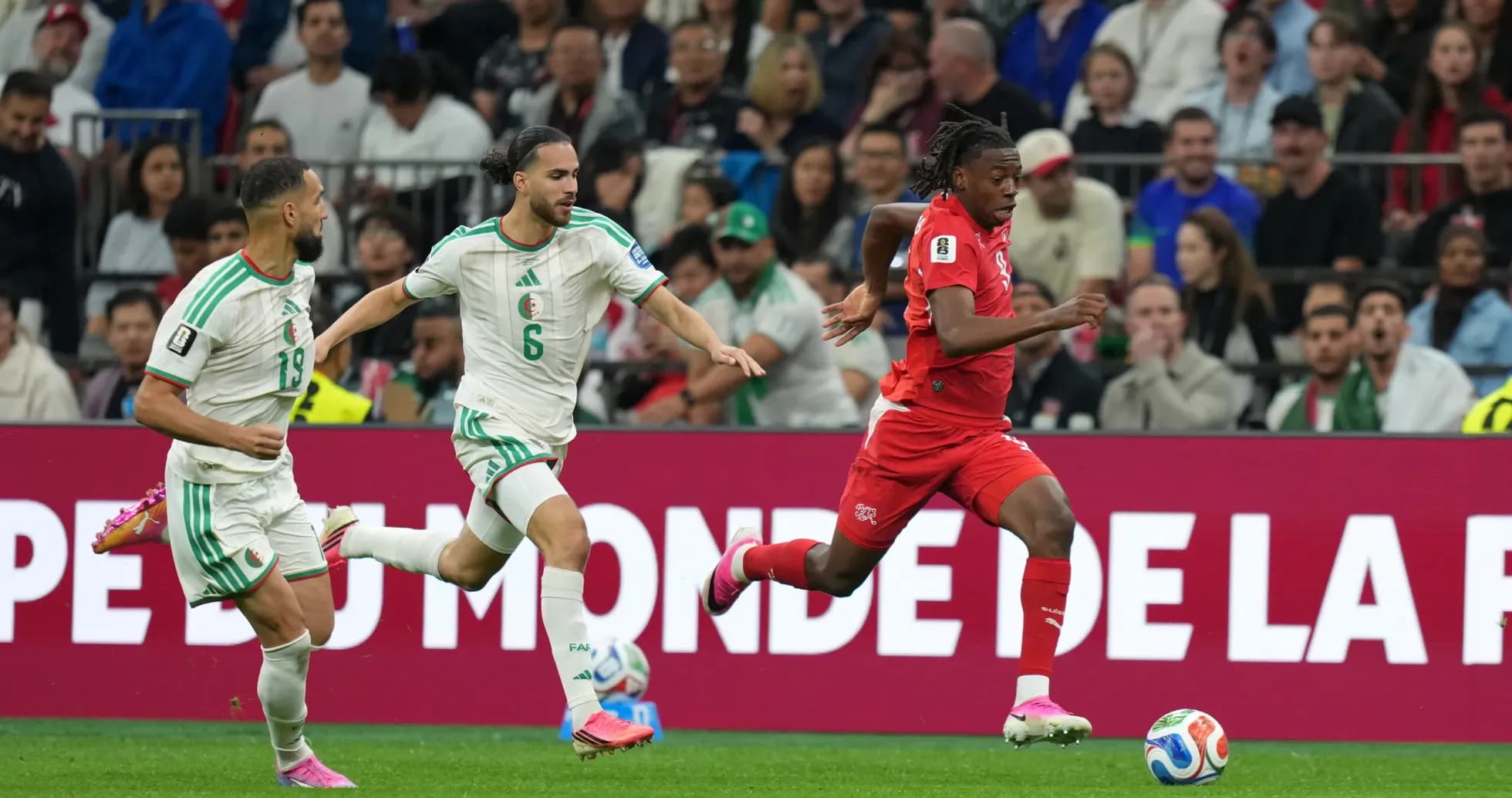 Switzerland player running past Algeria defenders