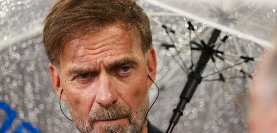 Coach under an umbrella during a press event