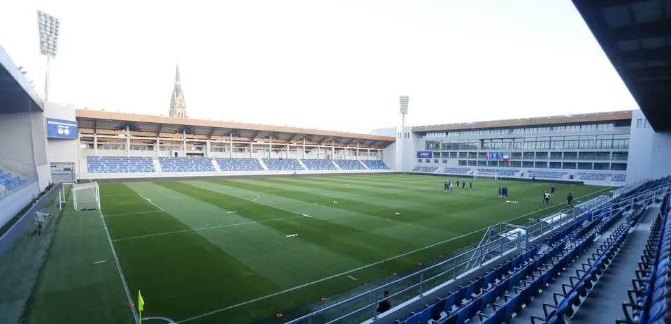 Empty football stadium with players training on field
