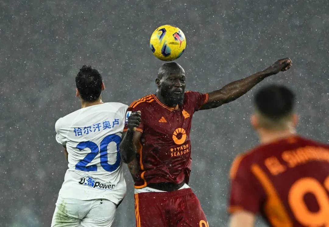 Players contesting a header in rainy match