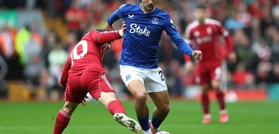 Everton player dribbling past Liverpool defender
