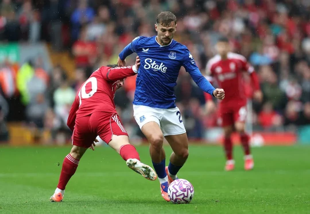 Everton player dribbling past Liverpool defender
