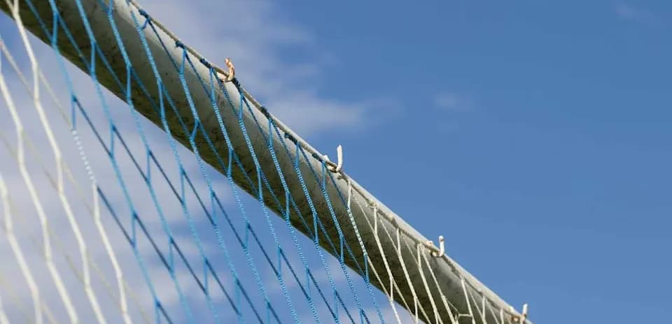 Close-up of a sports goal net against blue sky