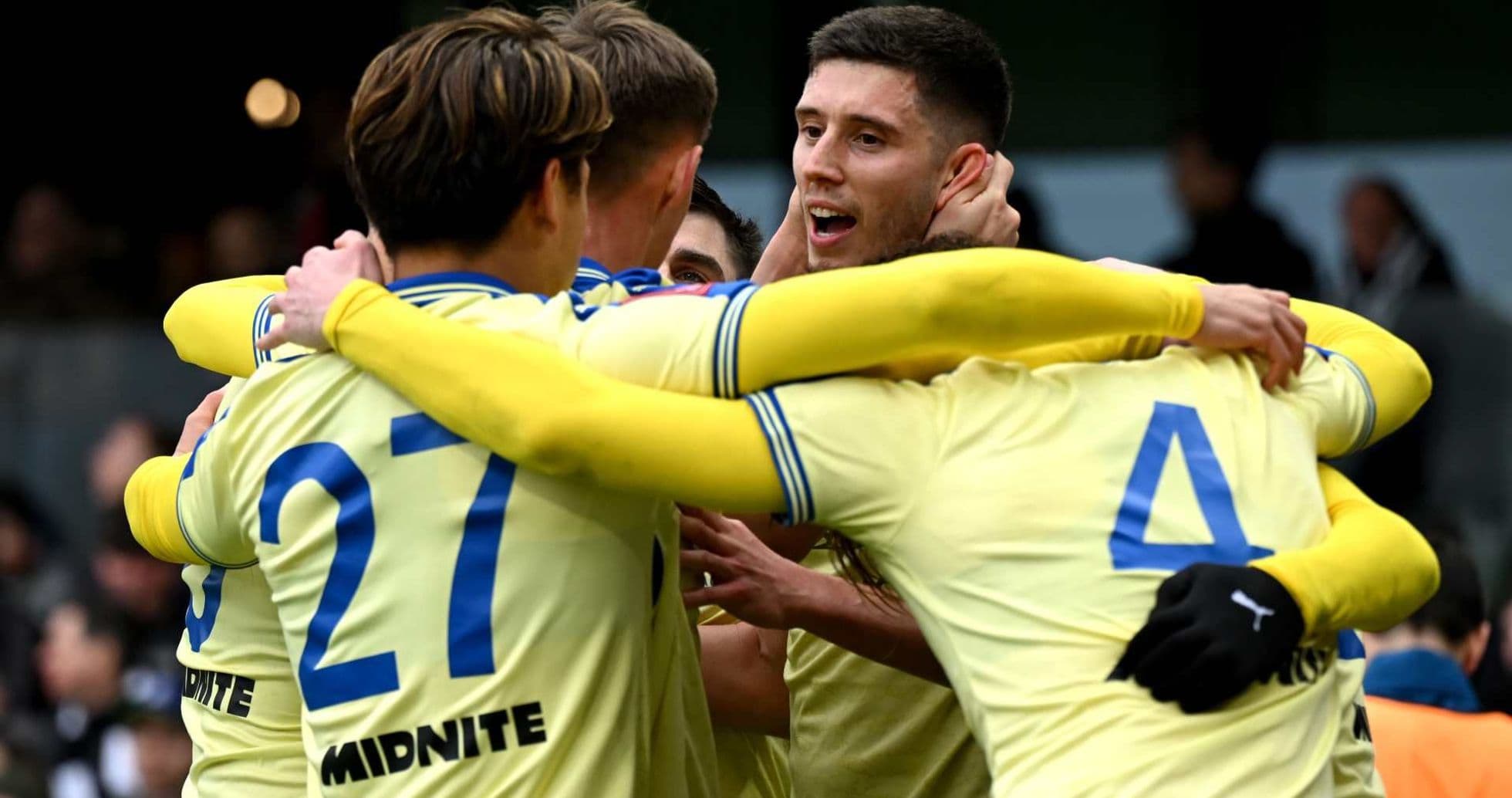 Players celebrating a goal in team jerseys