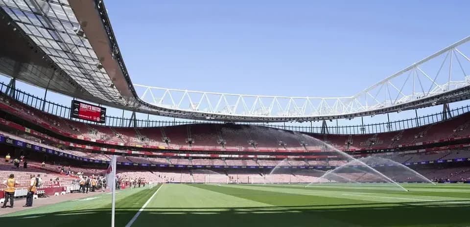 Empty stadium with sprinklers watering the pitch