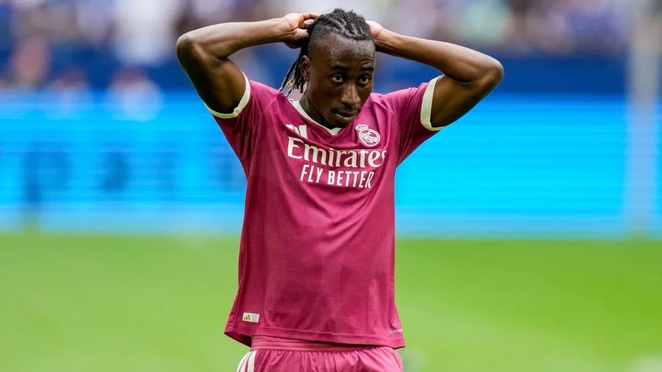 Player in pink kit with hands on head during match