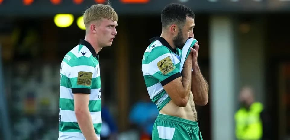 Two players in green and white jerseys walking off field