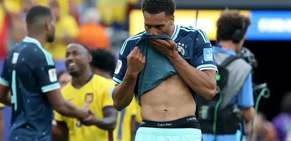 Player removing jersey after match, teammates in background