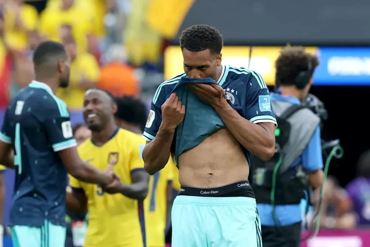Player removing jersey after match, teammates in background