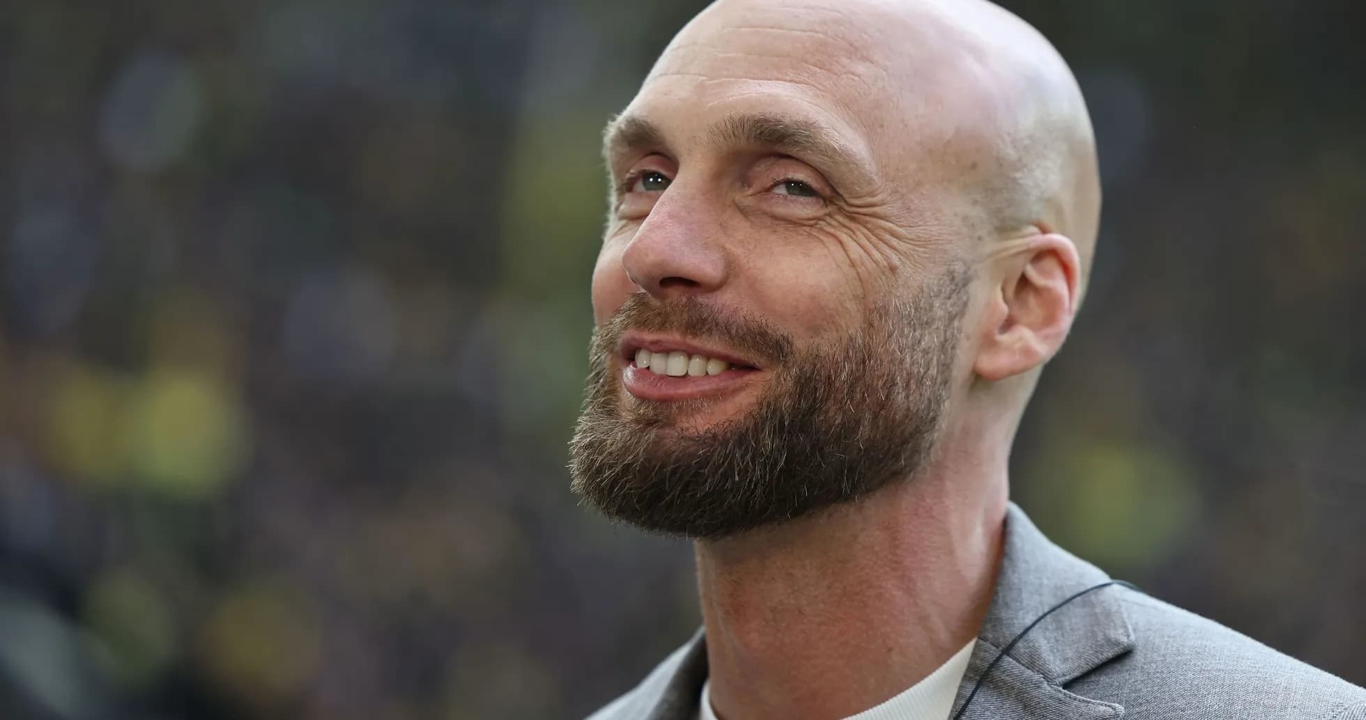 Man smiling in a gray blazer outdoors