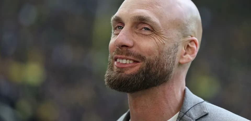 Man smiling in a gray blazer outdoors