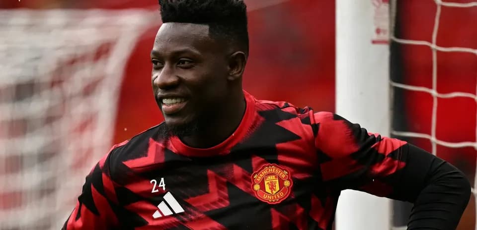 Goalkeeper in red and black kit smiling on pitch