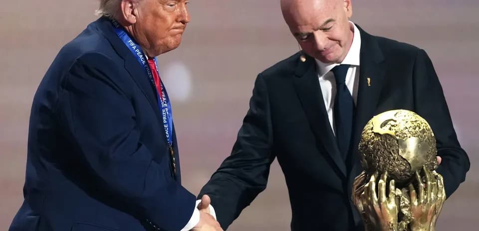 Two men shaking hands with FIFA Peace Prize trophy