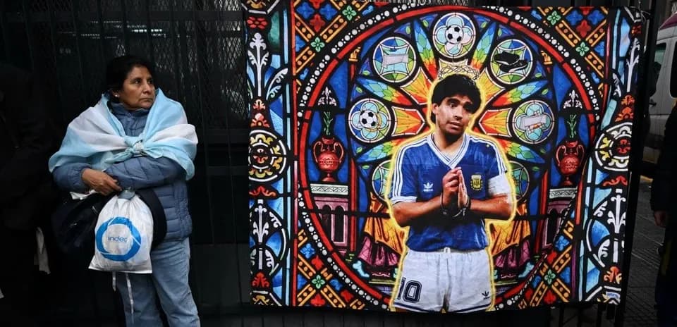 Woman with Argentine flag near Diego Maradona mural