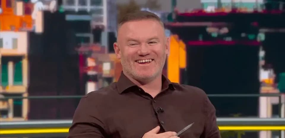 Man smiling while holding a pen on set