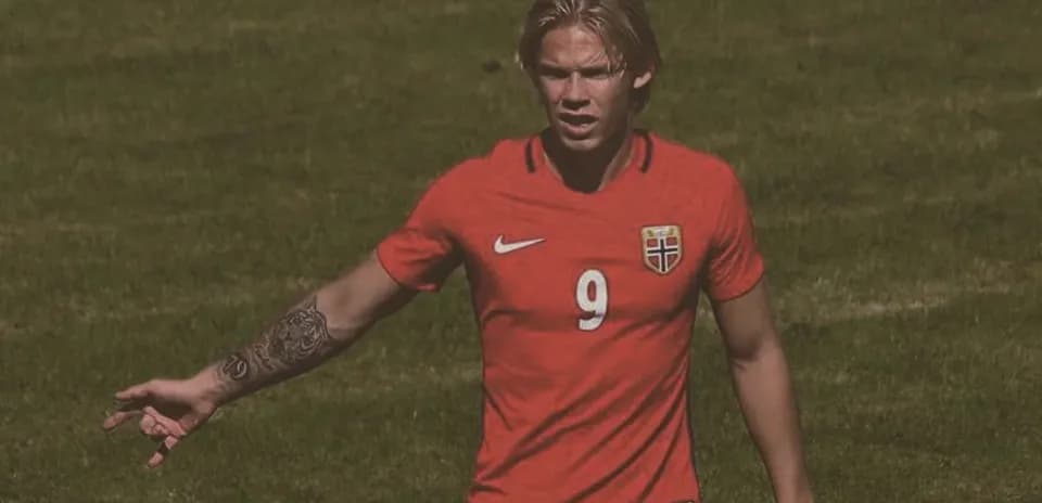 Player gesturing on the field in red jersey
