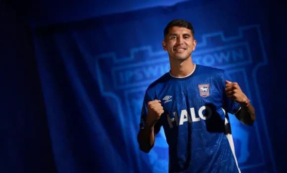 Player posing in Ipswich Town jersey with backdrop