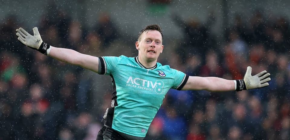 Goalkeeper celebrating with outstretched arms in rain