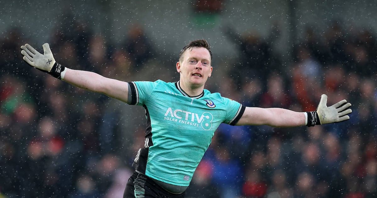 Goalkeeper celebrating with outstretched arms in rain