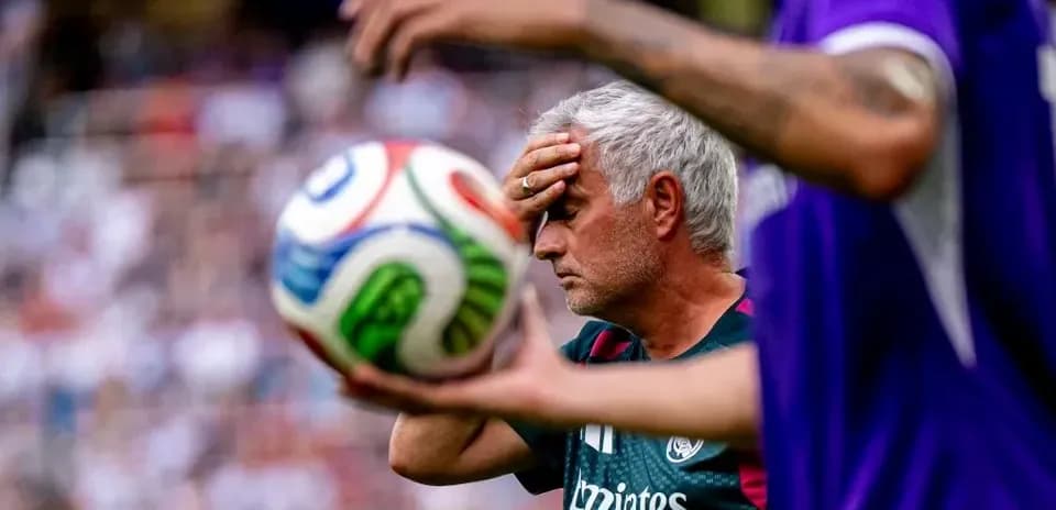 Coach with hand on forehead near soccer ball